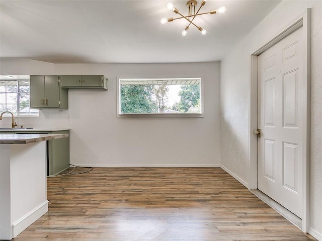 111 S Bristow Ave, Moore, OK 73160 - kitchen with green cabinetry, a chandelier, light wood-style flooring, and light countertops