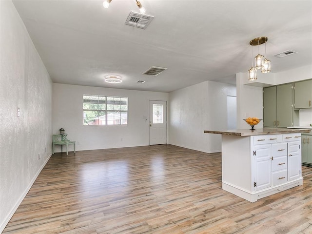 111 S Bristow Ave, Moore, OK 73160 - kitchen with light wood-style floors, green cabinets, open floor plan, a textured wall, and hanging light fixtures