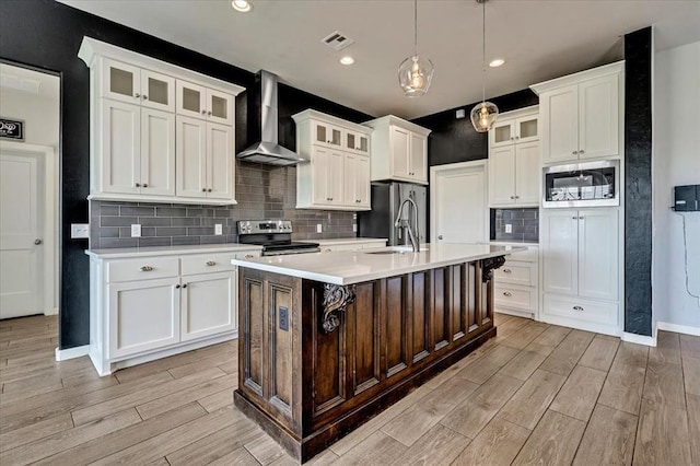 1069 Rheagen Kay Ave, Tuttle, OK 73089 - kitchen featuring wall chimney range hood, appliances with stainless steel finishes, light wood-type flooring, light countertops, and recessed lighting
