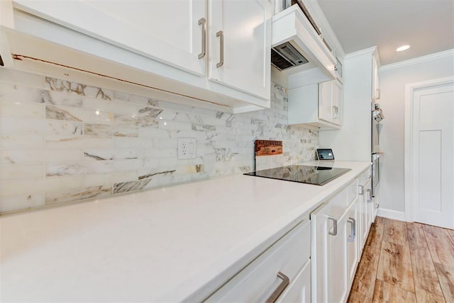 12629 Teakwood Rd, Oklahoma City, OK 73013 - kitchen with black electric cooktop, custom range hood, tasteful backsplash, white cabinetry, and crown molding