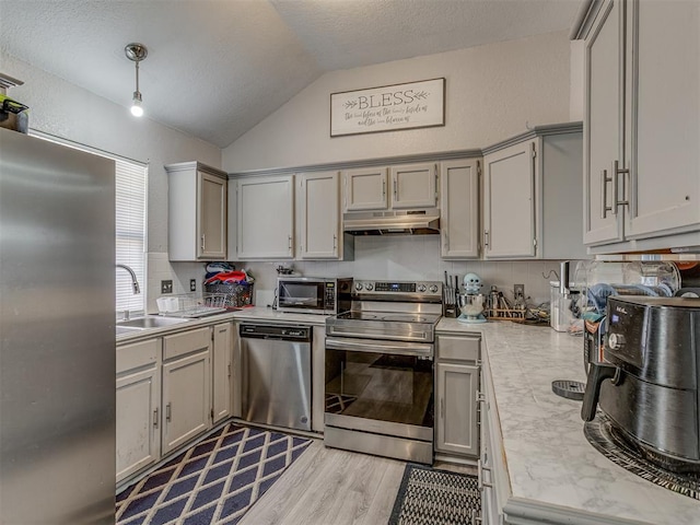 629 NW 121st St, Oklahoma City, OK 73114 - kitchen featuring stainless steel appliances, under cabinet range hood, lofted ceiling, light countertops, and gray cabinets