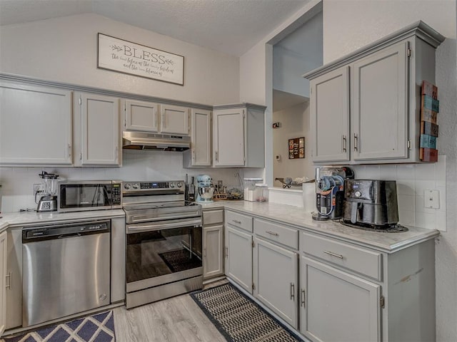 629 NW 121st St, Oklahoma City, OK 73114 - kitchen featuring stainless steel appliances, under cabinet range hood, light countertops, lofted ceiling, and light wood finished floors