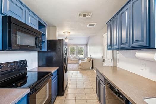 2709 NW 184th St, Edmond, OK 73012 - kitchen featuring black appliances, open floor plan, ceiling fan, light tile patterned floors, and blue cabinetry