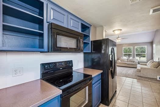 2709 NW 184th St, Edmond, OK 73012 - kitchen with black appliances, blue cabinetry, open floor plan, open shelves, and ceiling fan