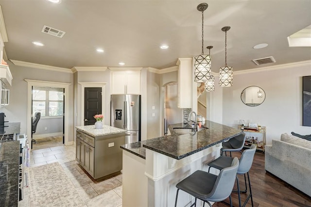 3937 NW 167th Ter, Edmond, OK 73012 - kitchen featuring appliances with stainless steel finishes, crown molding, dark stone countertops, a center island, and a kitchen breakfast bar