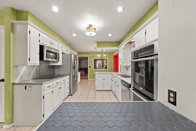 2805 Tudor Rd, Oklahoma City, OK 73127 - kitchen featuring stainless steel appliances, a peninsula, white cabinets, and recessed lighting