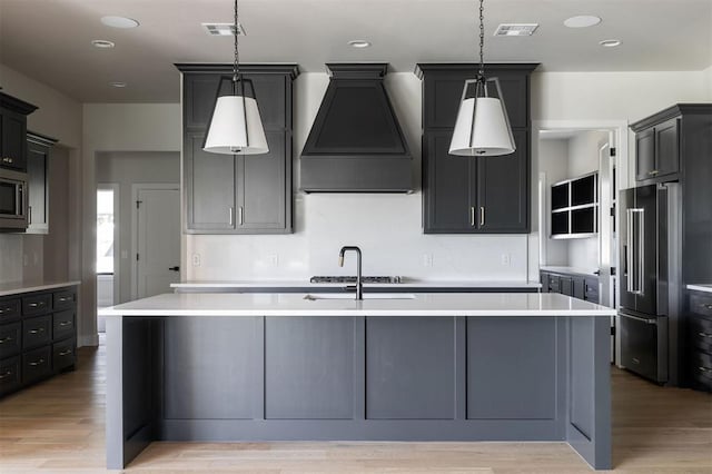 4716 Moulin Rd, Edmond, OK 73034 - kitchen with appliances with stainless steel finishes, premium range hood, light countertops, light wood finished floors, and recessed lighting