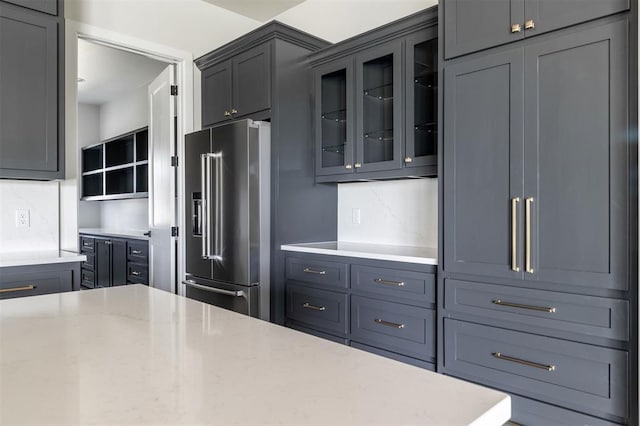 4716 Moulin Rd, Edmond, OK 73034 - kitchen featuring high end fridge, glass insert cabinets, light stone countertops, and decorative backsplash