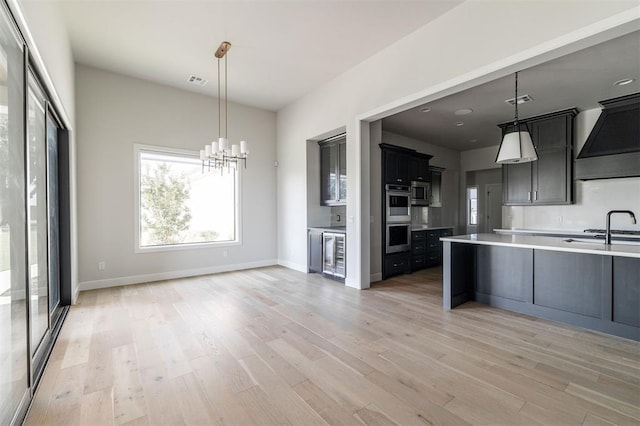 4716 Moulin Rd, Edmond, OK 73034 - kitchen with beverage cooler, light countertops, appliances with stainless steel finishes, light wood-style floors, and a chandelier