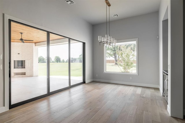4716 Moulin Rd, Edmond, OK 73034 - unfurnished dining area featuring light wood-style floors, a chandelier, a ceiling fan, and a fireplace