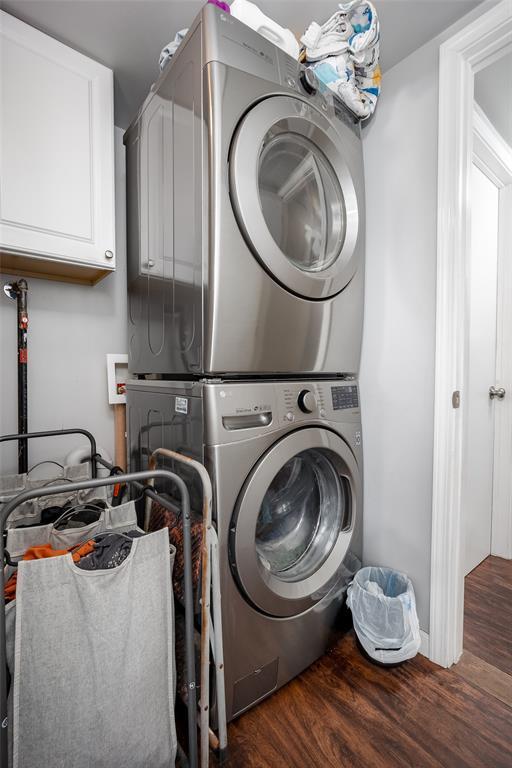 204 E Elder Ave, Duncan, OK 73533 - laundry room with stacked washing machine and dryer, cabinet space, and wood finished floors