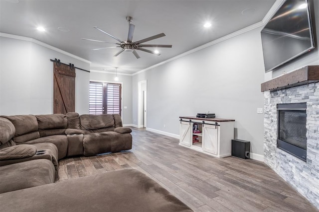 9125 NE Mustang Rd, Piedmont, OK 73078 - living room featuring a ceiling fan, wood finished floors, a fireplace, a barn door, and crown molding