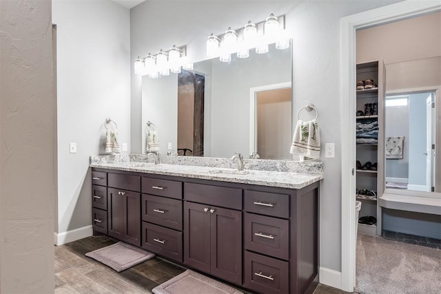 9125 NE Mustang Rd, Piedmont, OK 73078 - full bathroom with double vanity, a walk in closet, and wood finished floors