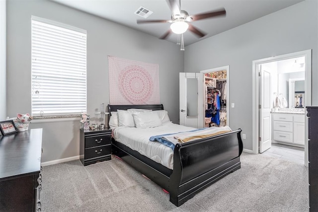 9125 NE Mustang Rd, Piedmont, OK 73078 - bedroom with light carpet, a walk in closet, connected bathroom, and a ceiling fan