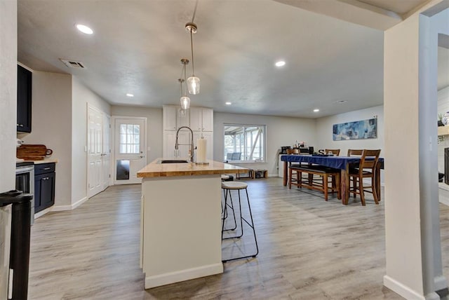 201 N English Dr, Moore, OK 73160 - kitchen with healthy amount of natural light, light wood-type flooring, a kitchen island with sink, a breakfast bar area, and recessed lighting