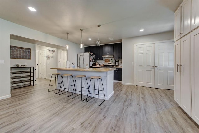 201 N English Dr, Moore, OK 73160 - kitchen featuring stainless steel range with electric stovetop, freestanding refrigerator, light countertops, a kitchen breakfast bar, and light wood-style floors