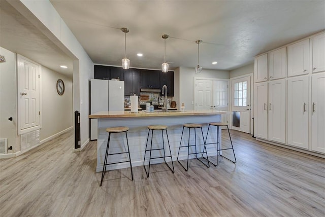 201 N English Dr, Moore, OK 73160 - kitchen featuring light wood finished floors, light countertops, a kitchen island with sink, recessed lighting, and a breakfast bar area
