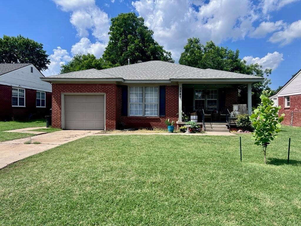 3847 NW 21st St, Oklahoma City, OK 73107 - view of front of home featuring a porch, a garage, concrete driveway, a front lawn, and brick siding