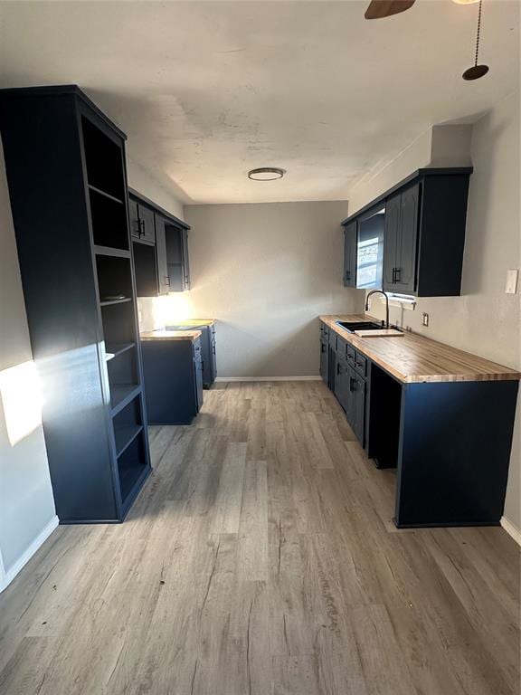 1501 W Watts St, El Reno, OK 73036 - kitchen featuring light wood-type flooring, open shelves, dark cabinets, light countertops, and a ceiling fan