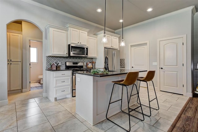 9920 NW 142nd St, Yukon, OK 73099 - kitchen featuring stainless steel appliances, ornamental molding, a breakfast bar, arched walkways, and backsplash