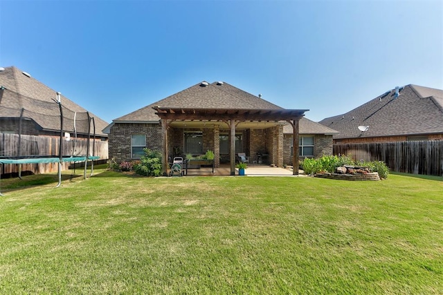 9920 NW 142nd St, Yukon, OK 73099 - back of property with a trampoline, brick siding, a patio area, a fenced backyard, and a shingled roof