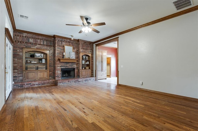 1723 Grey Hawk Rd, Edmond, OK 73003 - unfurnished living room with a ceiling fan, crown molding, wood finished floors, built in features, and a brick fireplace
