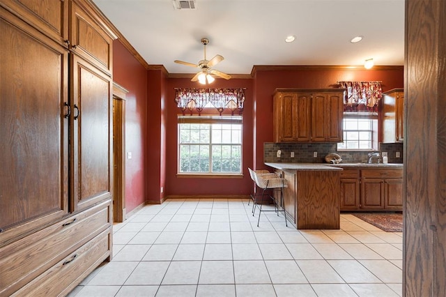 1723 Grey Hawk Rd, Edmond, OK 73003 - kitchen with a peninsula, a breakfast bar, crown molding, a ceiling fan, and light tile patterned floors