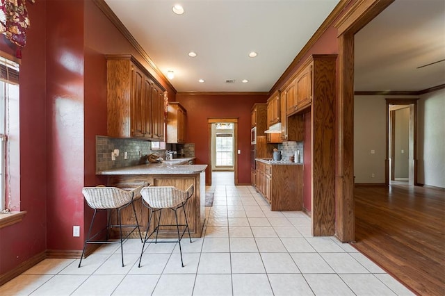 1723 Grey Hawk Rd, Edmond, OK 73003 - kitchen featuring crown molding, backsplash, recessed lighting, a peninsula, and under cabinet range hood