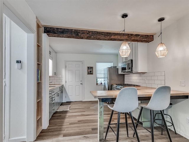2244 Downing St, Oklahoma City, OK 73120 - kitchen featuring stainless steel appliances, butcher block counters, a kitchen breakfast bar, decorative backsplash, and light wood-type flooring