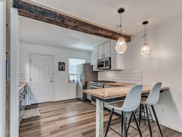 2244 Downing St, Oklahoma City, OK 73120 - kitchen with appliances with stainless steel finishes, butcher block counters, decorative backsplash, light wood-style flooring, and a kitchen bar