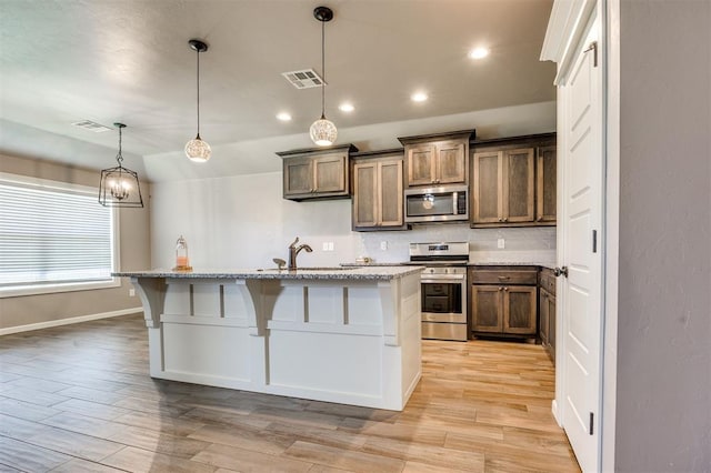 2208 Rivera Rd, Yukon, OK 73099 - kitchen with appliances with stainless steel finishes, tasteful backsplash, an island with sink, light wood-style flooring, and recessed lighting