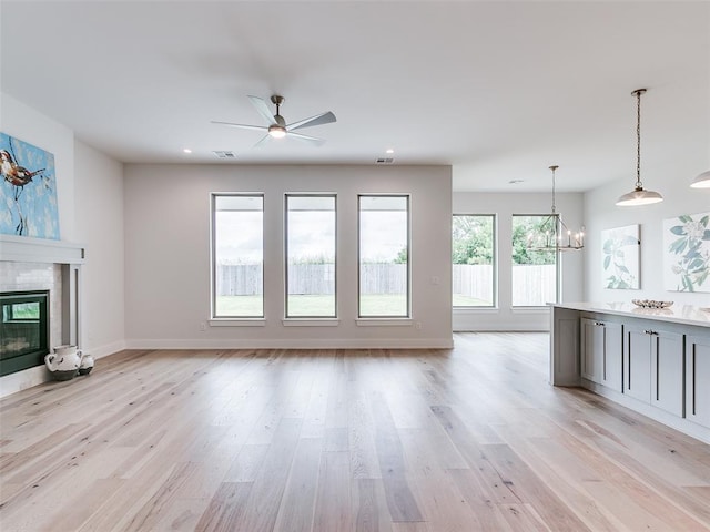 208 Pont Neuf Ct, Edmond, OK 73034 - unfurnished living room with a chandelier, a tile fireplace, light wood-style floors, a ceiling fan, and recessed lighting