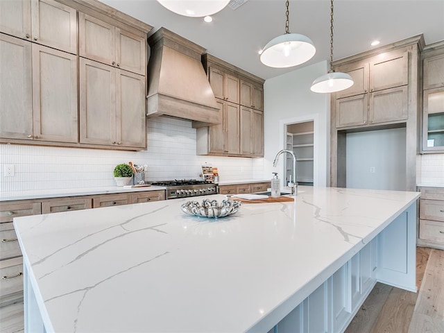 208 Pont Neuf Ct, Edmond, OK 73034 - kitchen with premium range hood, high end range, a large island, light wood-style floors, and tasteful backsplash