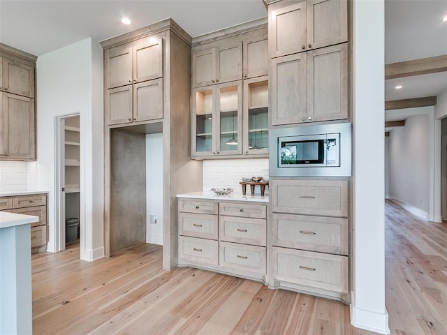 208 Pont Neuf Ct, Edmond, OK 73034 - kitchen with stainless steel microwave, light wood finished floors, decorative backsplash, light countertops, and recessed lighting