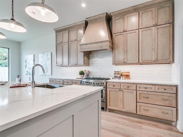 208 Pont Neuf Ct, Edmond, OK 73034 - kitchen featuring stainless steel stove, premium range hood, light wood finished floors, tasteful backsplash, and light stone countertops