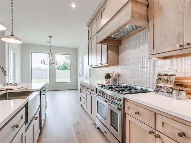 208 Pont Neuf Ct, Edmond, OK 73034 - kitchen featuring appliances with stainless steel finishes, premium range hood, light brown cabinets, tasteful backsplash, and light wood-style flooring