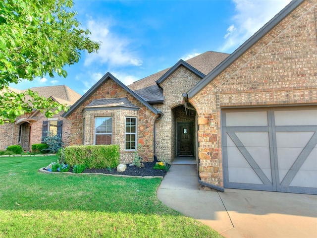 3205 NW 192nd Ter, Edmond, OK 73012 - view of front of house with a front lawn, an attached garage, a shingled roof, stone siding, and brick siding
