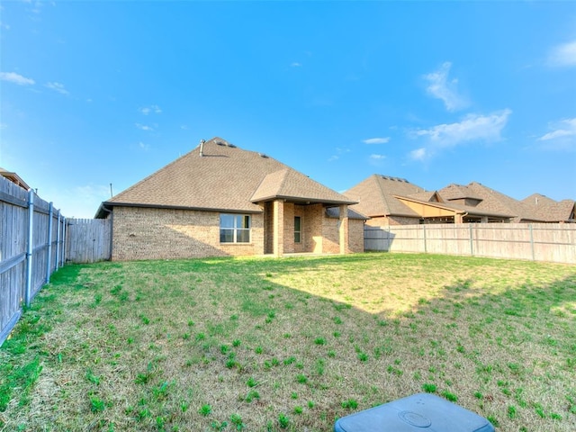 3205 NW 192nd Ter, Edmond, OK 73012 - back of house featuring a fenced backyard, brick siding, and roof with shingles
