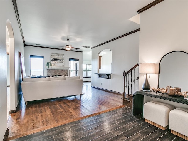 3205 NW 192nd Ter, Edmond, OK 73012 - living room featuring a ceiling fan, crown molding, stairway, arched walkways, and dark wood-type flooring