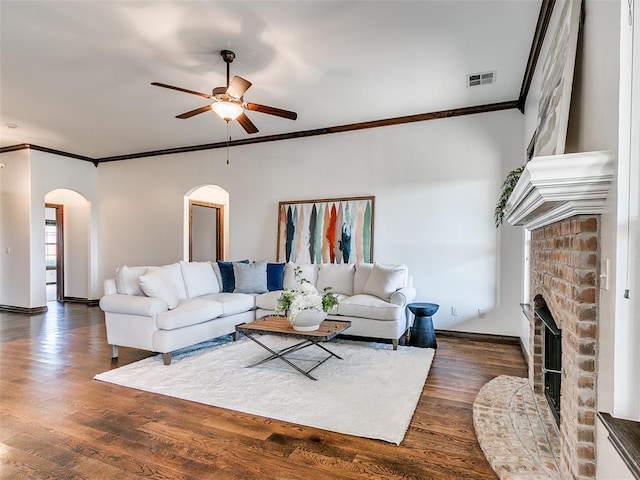 3205 NW 192nd Ter, Edmond, OK 73012 - living area featuring arched walkways, crown molding, ceiling fan, dark wood finished floors, and a fireplace