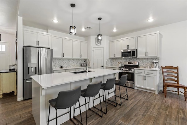 2666 Legacy Pl, Shawnee, OK 74804 - kitchen featuring stainless steel appliances, dark wood finished floors, tasteful backsplash, a kitchen island with sink, and recessed lighting