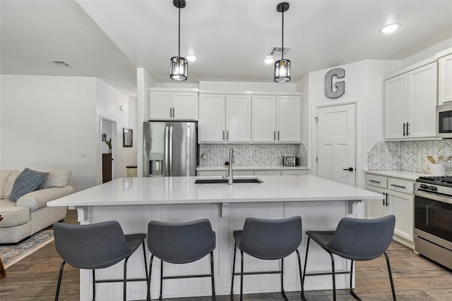 2666 Legacy Pl, Shawnee, OK 74804 - kitchen featuring stainless steel appliances, tasteful backsplash, dark wood-style floors, white cabinetry, and a kitchen breakfast bar