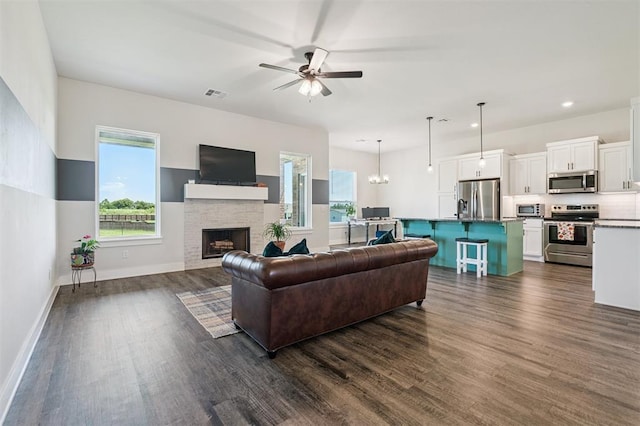 2316 Dixie Dr, Blanchard, OK 73010 - living room with dark wood-type flooring, ceiling fan, a fireplace, recessed lighting, and a chandelier