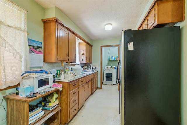 720 NW 16th St, Moore, OK 73160 - kitchen featuring freestanding refrigerator, light countertops, light flooring, brown cabinets, and a textured ceiling