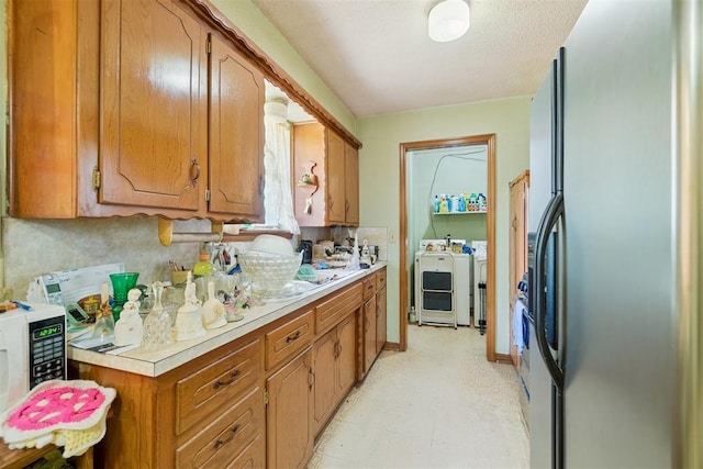 720 NW 16th St, Moore, OK 73160 - kitchen featuring washer and dryer, fridge with ice dispenser, light countertops, light flooring, and brown cabinetry