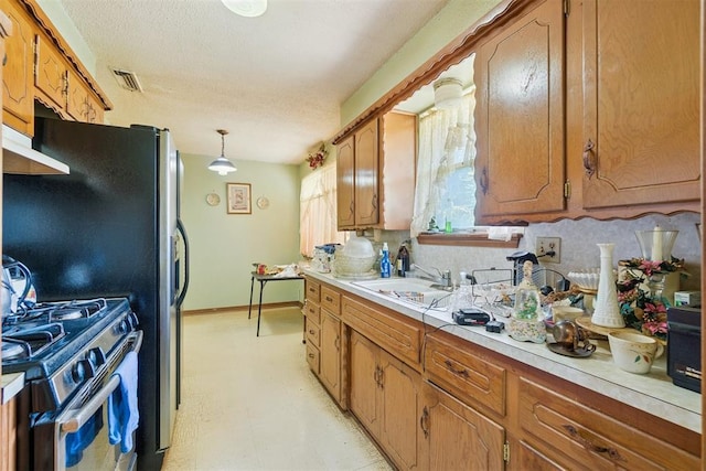 720 NW 16th St, Moore, OK 73160 - kitchen featuring gas range oven, light countertops, brown cabinets, under cabinet range hood, and light floors