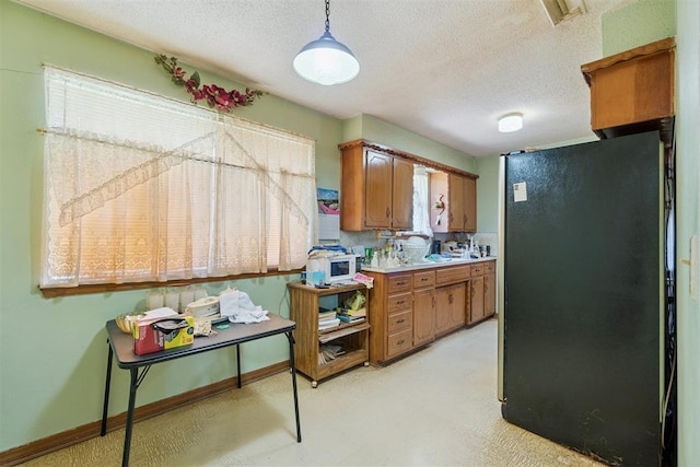 720 NW 16th St, Moore, OK 73160 - kitchen with freestanding refrigerator, brown cabinets, light countertops, light flooring, and a textured ceiling