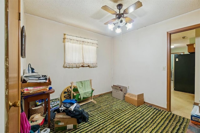 720 NW 16th St, Moore, OK 73160 - bedroom featuring carpet floors, freestanding refrigerator, a textured ceiling, and a ceiling fan