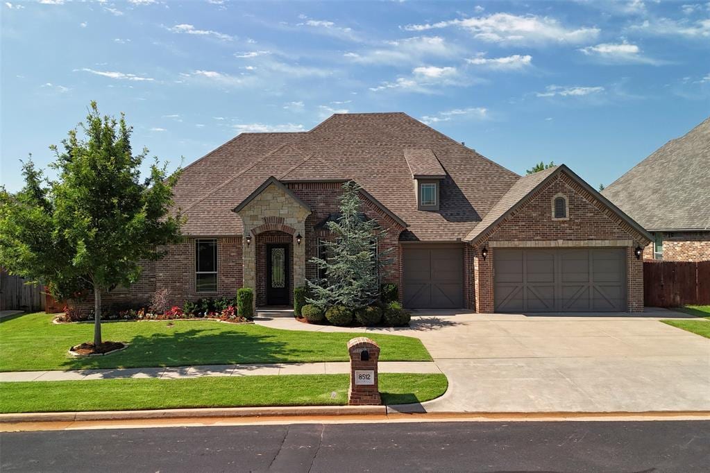 8512 NW 126th St, Oklahoma City, OK 73142 - french country home featuring brick siding, concrete driveway, a garage, and roof with shingles