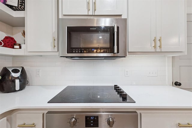 8 Corona Dr, Oklahoma City, OK 73149 - kitchen view of stainless steel microwave, oven, black electric stovetop, backsplash, and light countertops
